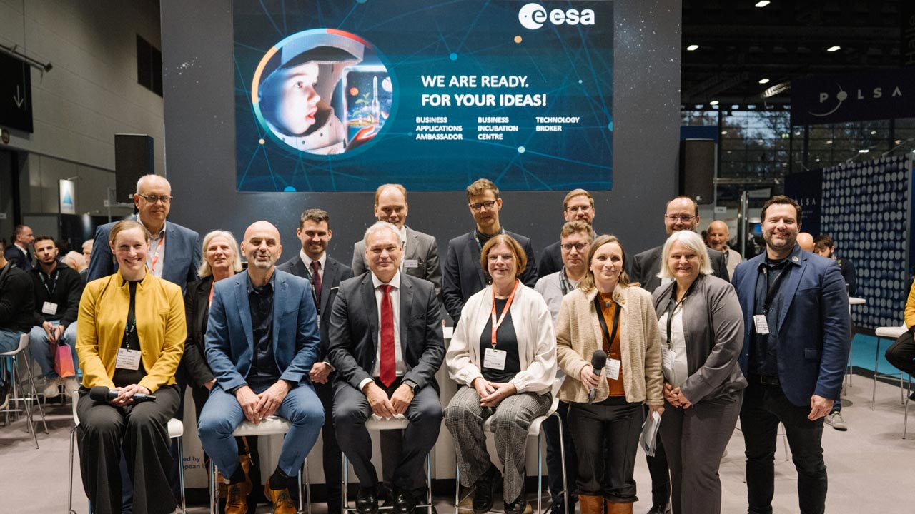 Auf dem Bild sind 16 Menschen zu sehen. Die erste Reihe sitzt auf Hochstühlen, die zweite Reihe steht, darunter die Gründerinnen. Im Hintergrund ist ein PPT-Chart der European Space Agency (ESA) zu erkennen. 